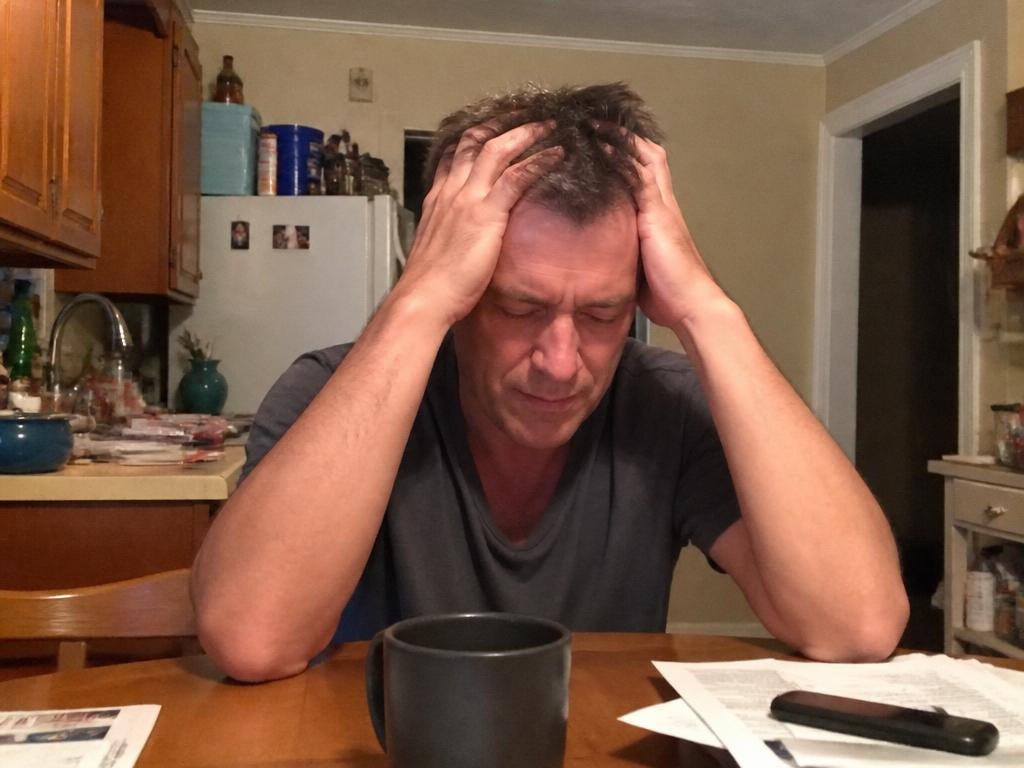 A stressed man at the kitchen table